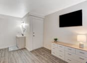 Thumbnail 33 of 56 - A room with a white door, a black screen on the wall, and a wooden bench with drawers underneath it.