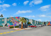 Thumbnail 45 of 56 - A wall with a colorful mural of a palm tree and a bird.
