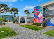 Thumbnail 36 of 56 - A colorful mural on a building in a sunny courtyard.