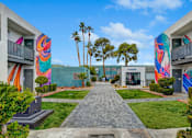 Thumbnail 35 of 56 - A walkway leads between two buildings with colorful murals on the walls.