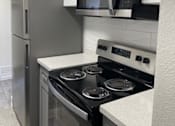Thumbnail 17 of 56 - A kitchen with a stove, refrigerator, and microwave.