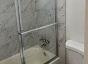 Thumbnail 19 of 56 - A white toilet sits next to a glass shower door.
