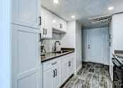 Thumbnail 24 of 56 - A kitchen with white cabinets and a wooden floor.