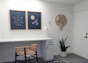 Thumbnail 31 of 56 - A room with a desk, chair, and two framed pictures on the wall.