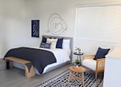 Thumbnail 30 of 56 - A bedroom with a bed, a bench, and a rug.