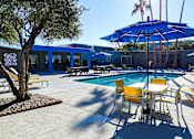 Thumbnail 39 of 56 - A pool area with a blue umbrella and yellow chairs.