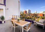 Thumbnail 3 of 14 - A table with chairs and a potted plant on a balcony overlooking a city.