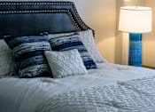 Thumbnail 11 of 15 - A bed with a white comforter and blue and white pillows.