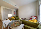 Thumbnail 6 of 15 - A living room with a green couch and a yellow throw pillow.