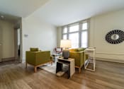 Thumbnail 7 of 15 - A living room with a green chair and a white table.