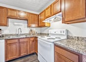 Thumbnail 4 of 15 - A kitchen with a white stove and wooden cabinets.