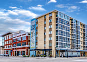 Thumbnail 2 of 10 - A modern multi-story building with a glass facade is the main focus of the image.
