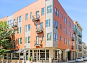Thumbnail 1 of 23 - A modern building with balconies on the second floor.