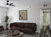 Thumbnail 13 of 18 - A living room with a brown sofa, a coffee table, and a painting on the wall.