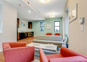 Thumbnail 14 of 23 - A living room with a grey couch and red chairs.