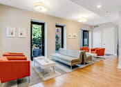 Thumbnail 4 of 23 - A living room with a white couch and orange chairs.
