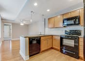 Thumbnail 3 of 23 - A kitchen with wooden cabinets and black appliances.