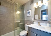 Thumbnail 10 of 10 - A modern bathroom with a glass shower stall and a white toilet.