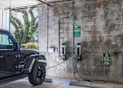 Thumbnail 28 of 33 - A black Jeep is charging at an electric vehicle charging station.