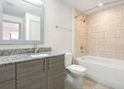 Thumbnail 10 of 33 - A bathroom with a white tub, sink, and toilet.