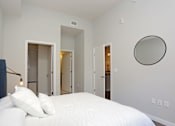 Thumbnail 8 of 33 - A bedroom with a large bed and a mirror on the wall.