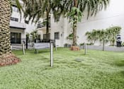 Thumbnail 21 of 33 - A white building with a green lawn and palm trees.