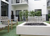 Thumbnail 31 of 33 - A modern outdoor seating area with a fire pit in the center.