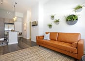 Thumbnail 3 of 33 - A living room with a brown couch and a white wall.