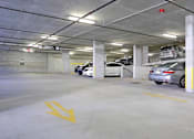 Thumbnail 27 of 33 - A parking garage with cars parked and a yellow arrow on the ground.