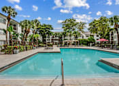 Thumbnail 11 of 18 - A swimming pool surrounded by palm trees and lounge chairs.
