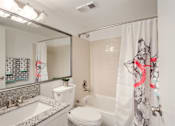 Thumbnail 9 of 18 - A bathroom with a white toilet, sink, and shower curtain.