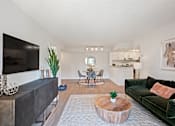 Thumbnail 5 of 18 - A living room with a green couch and a wooden coffee table.