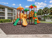 Thumbnail 15 of 18 - A playground with a yellow slide and a green slide.