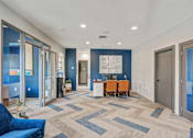 Thumbnail 17 of 18 - A hallway with a blue couch and a table with chairs.