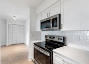 Thumbnail 22 of 29 - A kitchen with a black stove top oven and white cabinets.