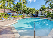 Thumbnail 3 of 29 - A large swimming pool surrounded by palm trees and lounge chairs.