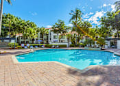 Thumbnail 5 of 29 - A large outdoor swimming pool surrounded by palm trees.