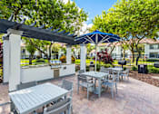 Thumbnail 6 of 29 - A patio with a table and chairs under a blue umbrella.