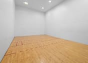 Thumbnail 13 of 29 - A squash court with a wooden floor and white walls.