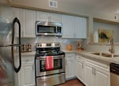 Thumbnail 26 of 29 - A kitchen with white cabinets and stainless steel appliances.