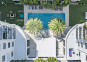 Thumbnail 15 of 33 - A white building with a pool and palm trees.
