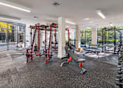 Thumbnail 16 of 33 - A gym with a variety of equipment including a squat rack, bench, and weights.