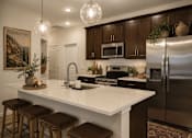 Thumbnail 46 of 47 - A kitchen with a white countertop and brown stools.