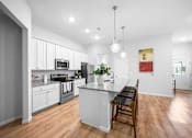 Thumbnail 5 of 33 - A kitchen with a white island and a dining table.