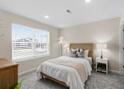 Thumbnail 18 of 26 - A bedroom with a large bed and a nightstand with a lamp.