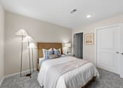 Thumbnail 17 of 26 - A bedroom with a large bed and a lamp.