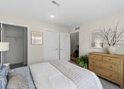Thumbnail 16 of 26 - A bedroom with a large bed, a dresser, and a mirror.