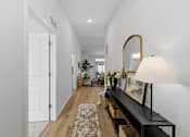 Thumbnail 1 of 26 - A hallway with a bench, lamp, and mirror.