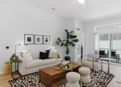Thumbnail 10 of 26 - A living room with a white couch, a coffee table, and a large window.
