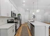 Thumbnail 4 of 26 - A modern kitchen with white cabinets and stainless steel appliances.